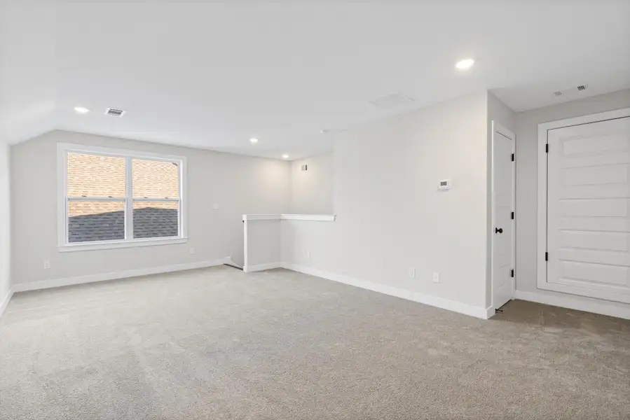Spacious room with light-toned carpeting, ample window light, and recessed ceiling fixtures Spacious room with light-toned carpeting, ample window light, and recessed ceiling fixtures