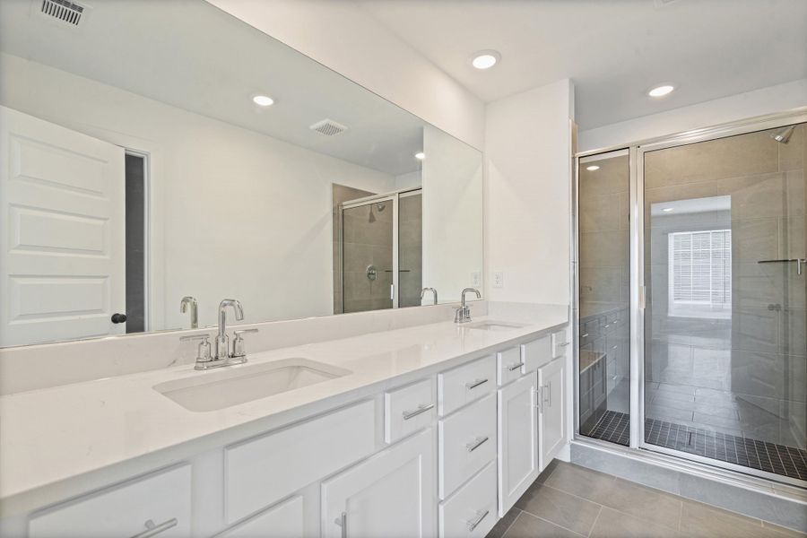 Dual vanity with undermount sinks, an expansive mirror, a glass-enclosed shower, tiled flooring, and recessed lighting Dual vanity with undermount sinks, an expansive mirror, a glass-enclosed shower, tiled flooring, and recessed lighting