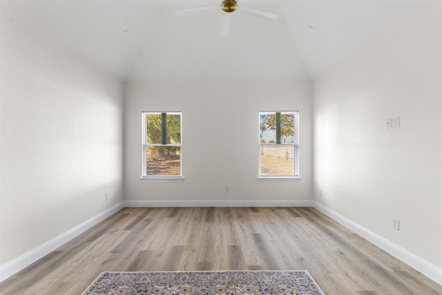 Spare room featuring ceiling fan, high vaulted ceiling, light hardwood / wood-style flooring, and plenty of natural light