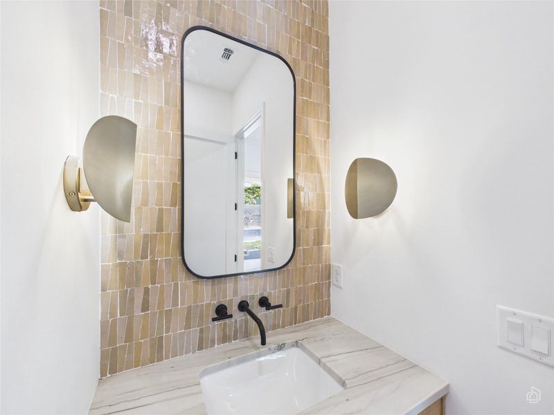 Textured tile backsplashes and stone countertops elevate this contemporary bathroom vanity space.