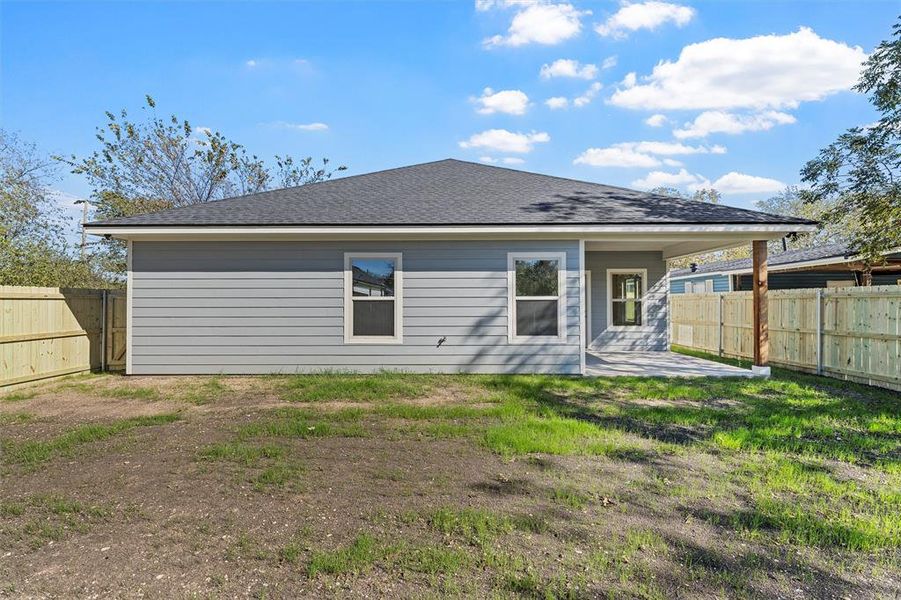 Back of property featuring a patio, a fenced backyard, and roof with shingles