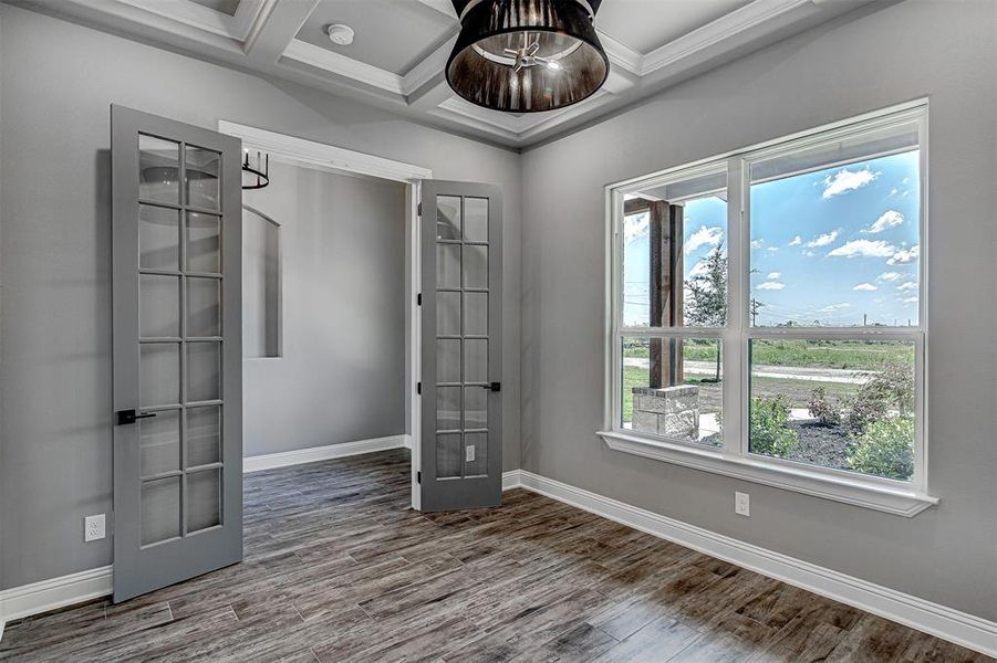 Empty room with wood-type flooring, beamed ceiling, french doors, and coffered ceiling