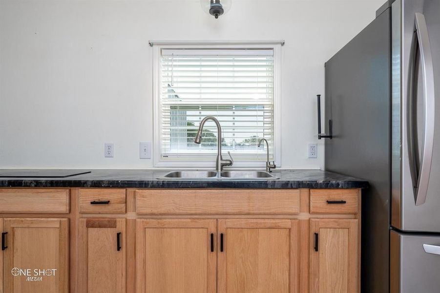 Kitchen featuring stainless steel fridge, sink, and light brown cabinetry
