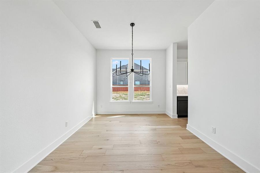 Unfurnished dining area featuring a chandelier and light wood-style floors