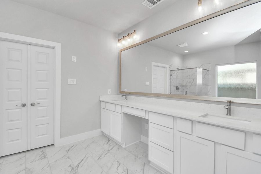 Elevate your daily routine at the elegant vanity, now equipped with double sinks, light countertops, modern hardware, and beautiful vanity lights.