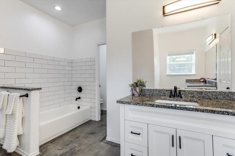 Bathroom featuring a white vanity with granite countertop, undermount sink, and black fixtures
