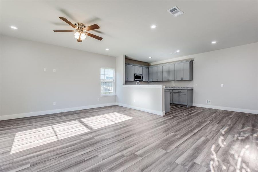 Unfurnished living room featuring ceiling fan and light wood-type flooring