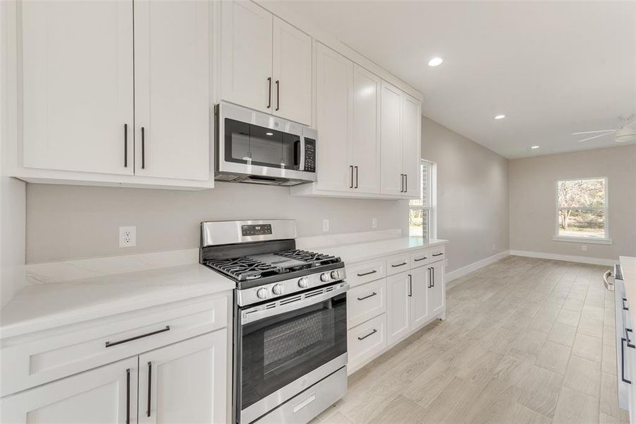 Kitchen featuring stainless steel appliances, white cabinetry, a wealth of natural light, and ceiling fan