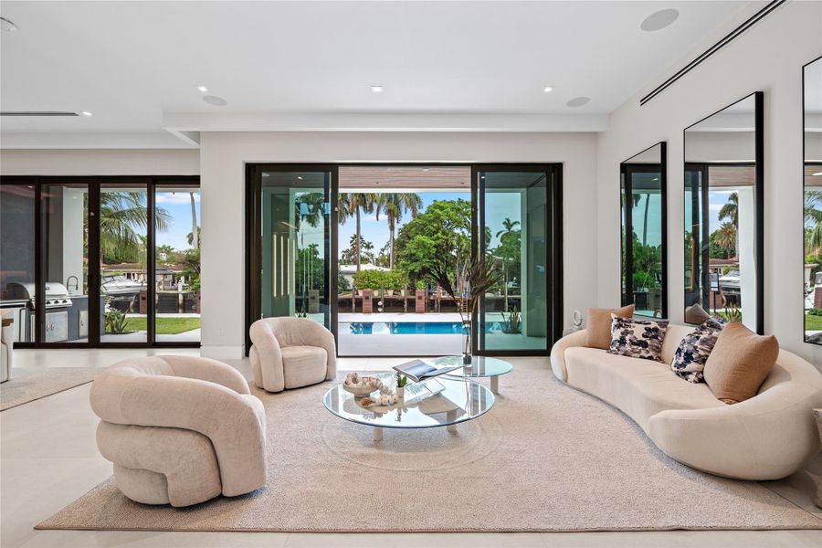 Stylish living room with modern designer furnishings, glass walls opening to the pool, and seamless indoor-outdoor living. Stylish living room with modern designer furnishings, glass walls opening to the pool, and seamless indoor-outdoor living.