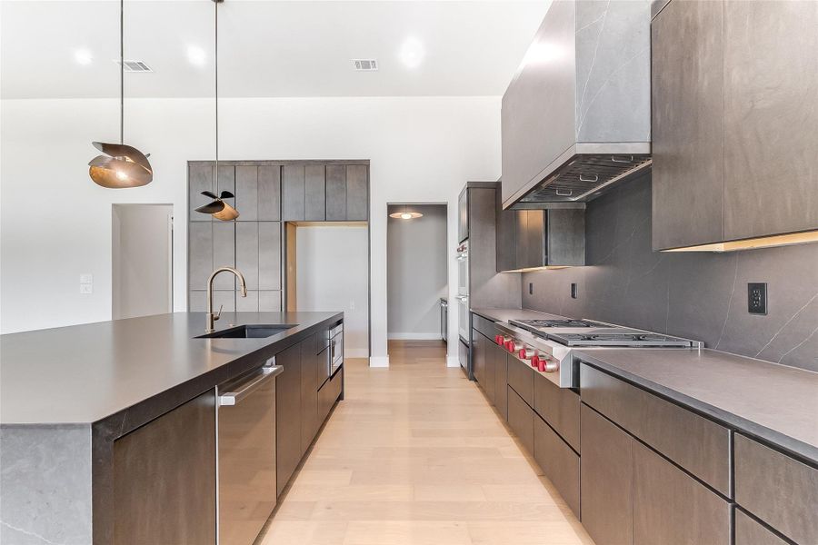 Kitchen featuring a sink, stainless steel appliances, modern cabinets, custom range hood, and backsplash Kitchen featuring a sink, stainless steel appliances, modern cabinets, custom range hood, and backsplash