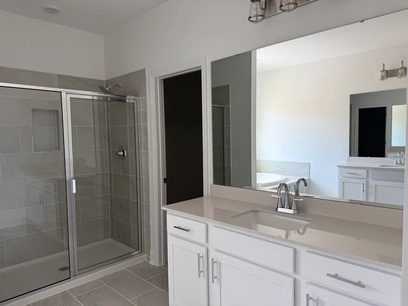 Primary Bath featuring the AW Collection® Coastal - Spa-like with white cabinets and light tile. Primary Bath featuring the AW Collection® Coastal - Spa-like with white cabinets and light tile.