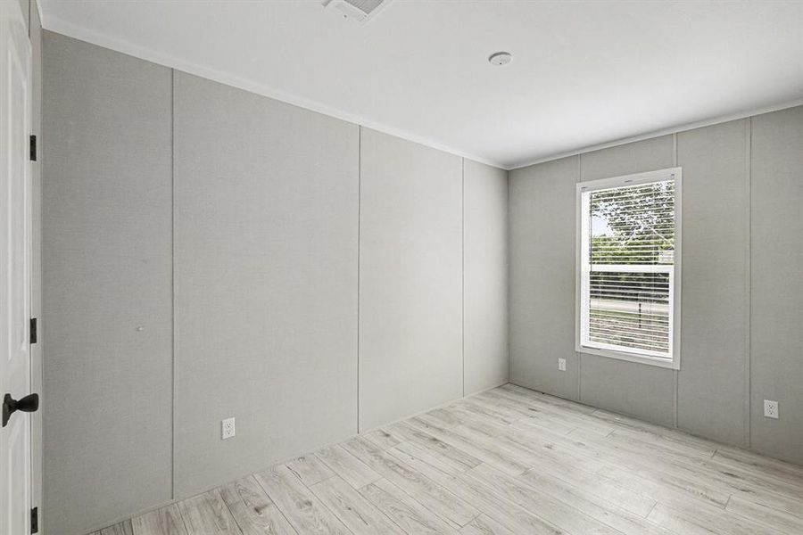 Room featuring light wood-look flooring, paneled walls, and white trim and closet