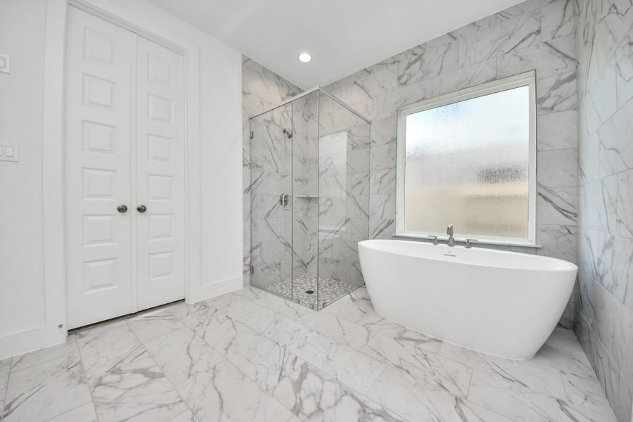Indulge in a spa-like retreat within the confines of this primary bathroom. Delight in a spacious walk-in shower enveloped in stylish tile surround, unwind in a separate garden tub adorned with custom detailing.