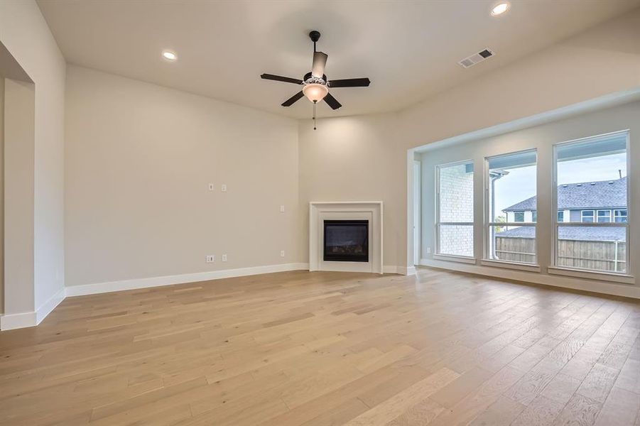 Unfurnished living room featuring light wood-type flooring, a ceiling fan, a glass covered fireplace, and recessed lighting