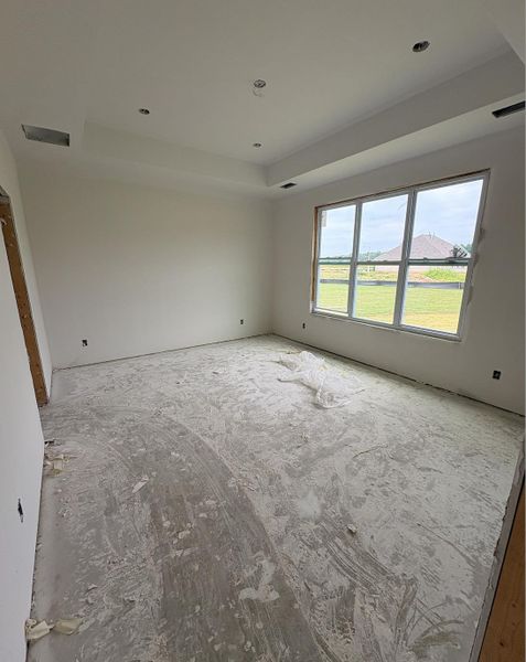 Spacious room featuring a tray ceiling with recessed lighting, large multi-pane window, and primed walls Spacious room featuring a tray ceiling with recessed lighting, large multi-pane window, and primed walls
