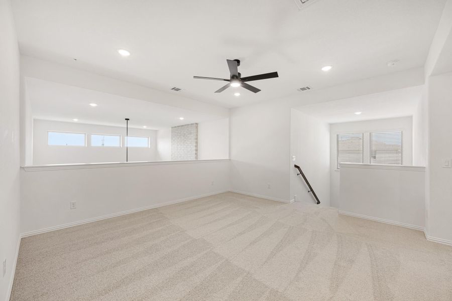 Open upstairs loft with beige carpet, ceiling fan, recessed lighting, and staircase opening Open upstairs loft with beige carpet, ceiling fan, recessed lighting, and staircase opening