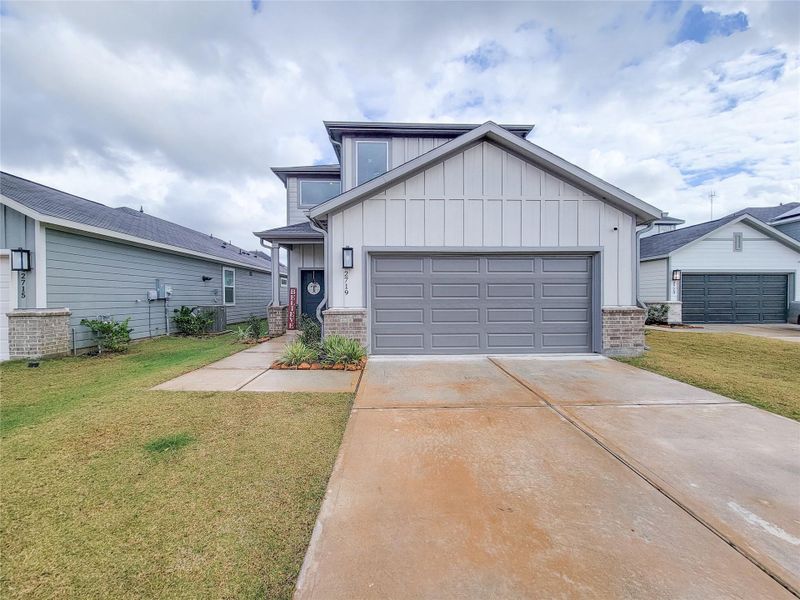 Modern two-story home with a clean, gray exterior and a spacious two-car garage. Features a well-maintained front lawn and a welcoming entrance.