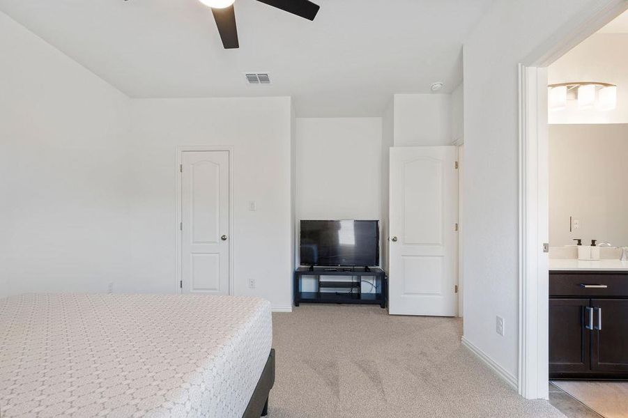 Bedroom featuring light carpet, ensuite bath, and ceiling fan Bedroom featuring light carpet, ensuite bath, and ceiling fan