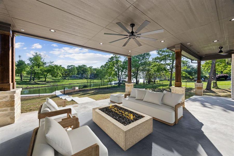 Fenced backyard with ceiling fan, an outdoor living space with a fire pit, and a patio area Fenced backyard with ceiling fan, an outdoor living space with a fire pit, and a patio area