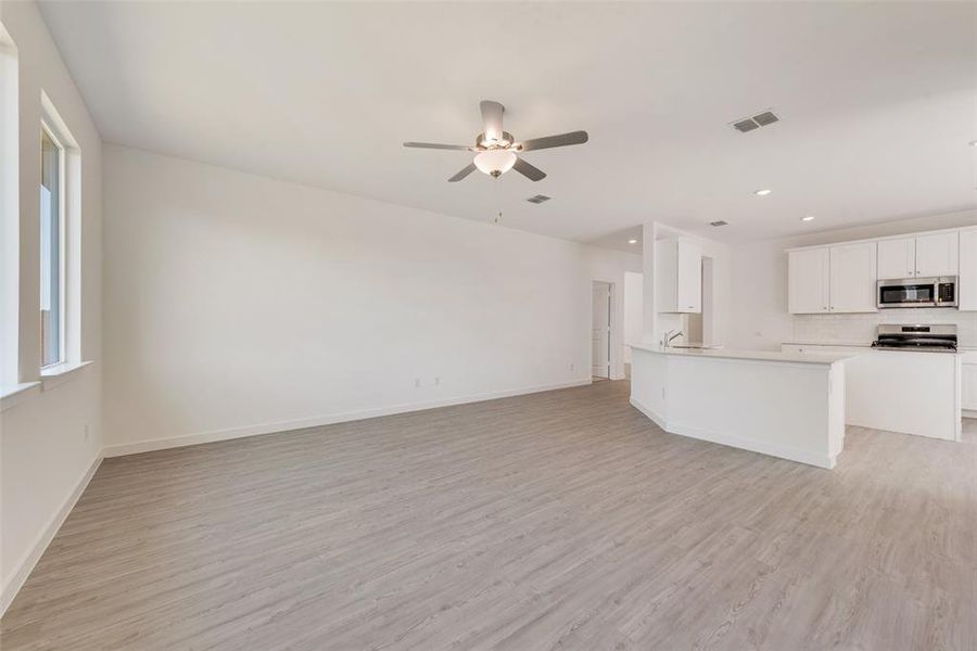 Kitchen with white cabinetry, ceiling fan, kitchen peninsula, appliances with stainless steel finishes, and light wood-type flooring