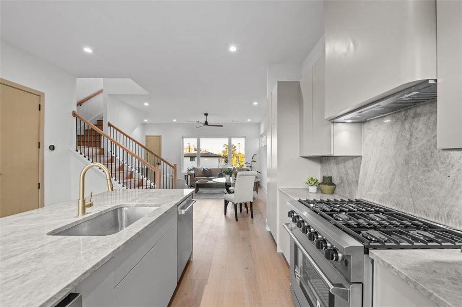 Kitchen with high end stainless steel range, white cabinets, ceiling fan, light wood-type flooring, and recessed lighting