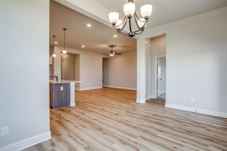 Unfurnished dining area featuring sink, ceiling fan with notable chandelier, and light hardwood / wood-style flooring