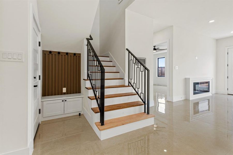 Stairway with a glass covered fireplace, recessed lighting, marble finish floor, and ceiling fan