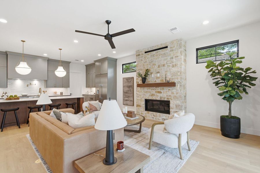 A stone fireplace anchors the open living space, seamlessly connecting to the modern kitchen.