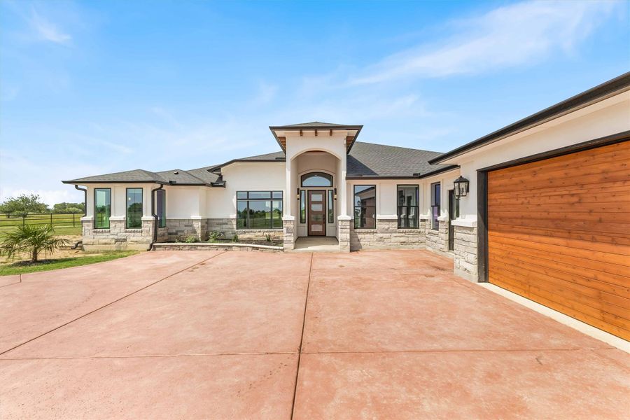 View of front of home with stone siding, stucco siding, and a garage View of front of home with stone siding, stucco siding, and a garage