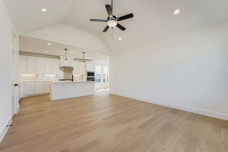 Unfurnished living room featuring vaulted ceiling, light wood-style flooring, recessed lighting, and ceiling fan Unfurnished living room featuring vaulted ceiling, light wood-style flooring, recessed lighting, and ceiling fan