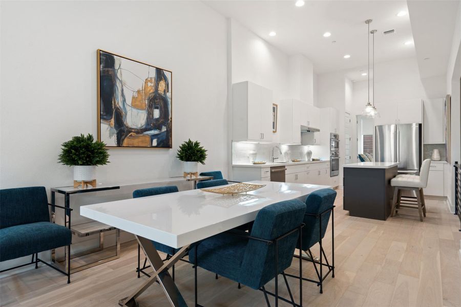 Dining area featuring a high ceiling, light wood-style floors, and recessed lighting