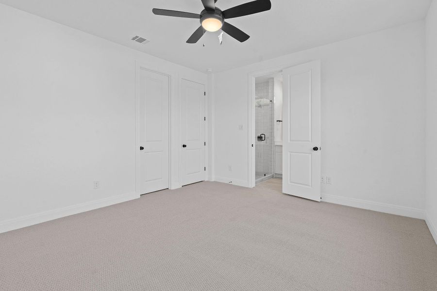 Unfurnished bedroom with light colored carpet, ensuite bathroom, and a ceiling fan Unfurnished bedroom with light colored carpet, ensuite bathroom, and a ceiling fan