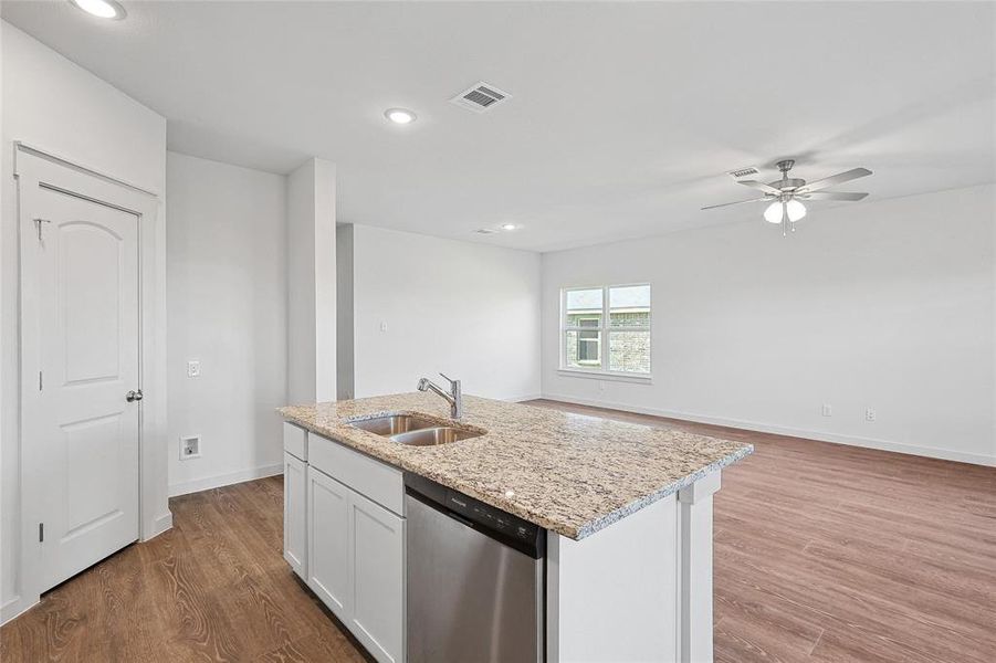 Kitchen featuring light wood-type flooring, a kitchen island with sink, sink, white cabinetry, and stainless steel dishwasher