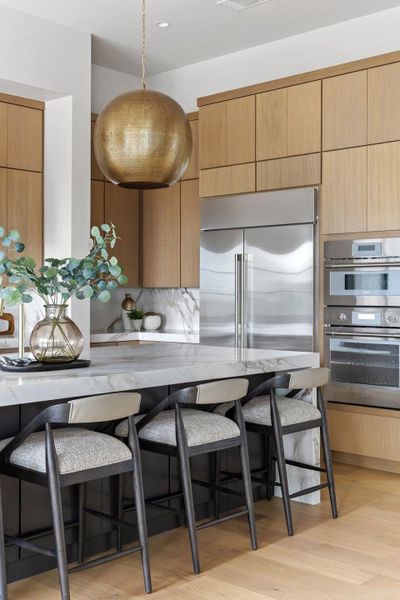 Kitchen island featuring a substantial white stone countertop and a brass spherical pendant light fixture