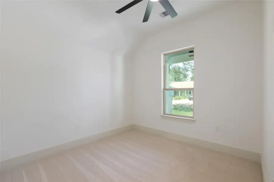 Unfurnished room featuring light carpet, vaulted ceiling, and a ceiling fan