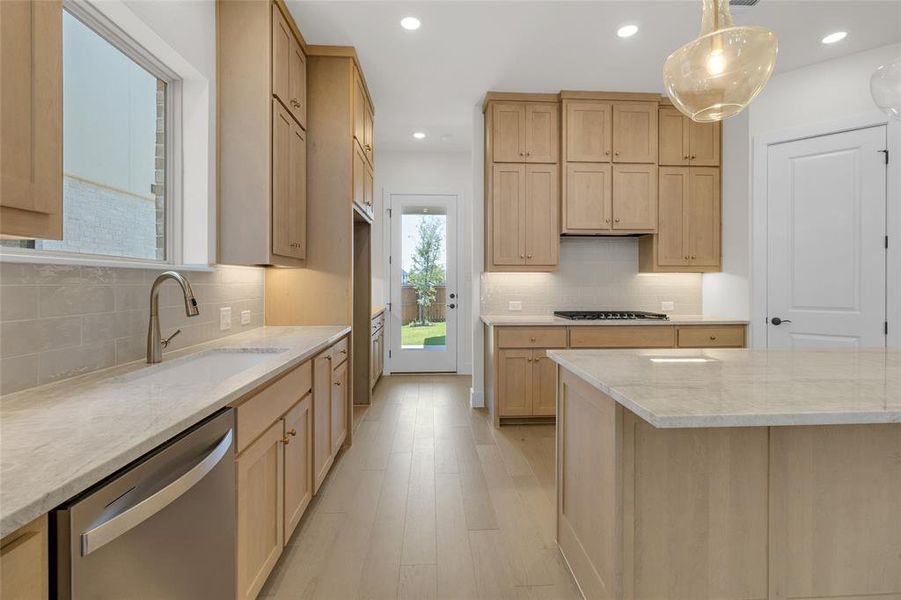 Contemporary kitchen featuring light wood cabinetry, stone countertops, stainless steel appliances, and wood-finish flooring