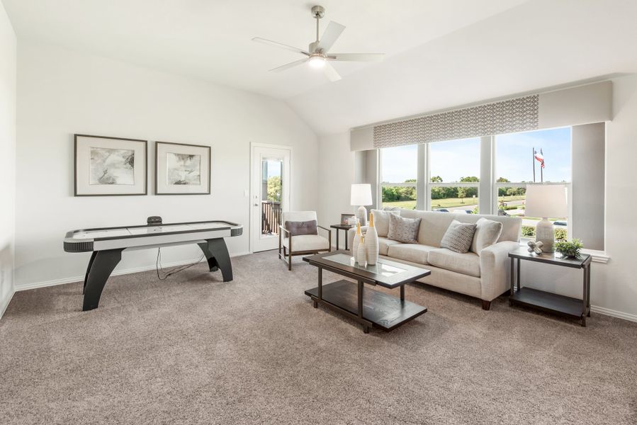 Bonus room with carpet, air hockey table, sofa seating, and ceiling fan near large windows
