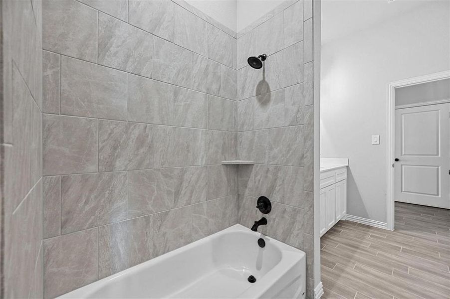 Full bathroom featuring washtub / shower combination, wood tiled floors, and vanity Full bathroom featuring washtub / shower combination, wood tiled floors, and vanity