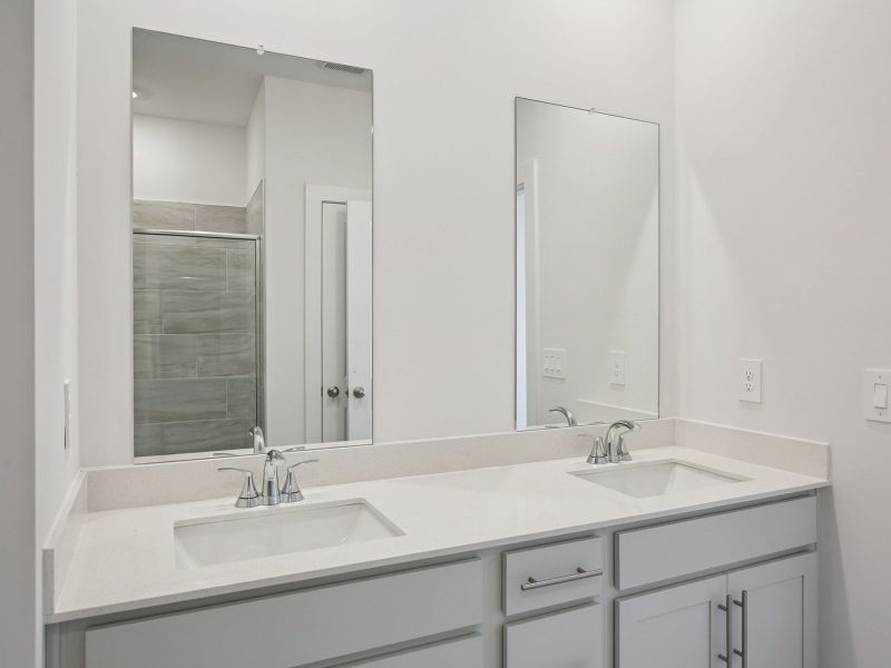 The primary bathroom offers dual vanity sinks and a walk-in shower.