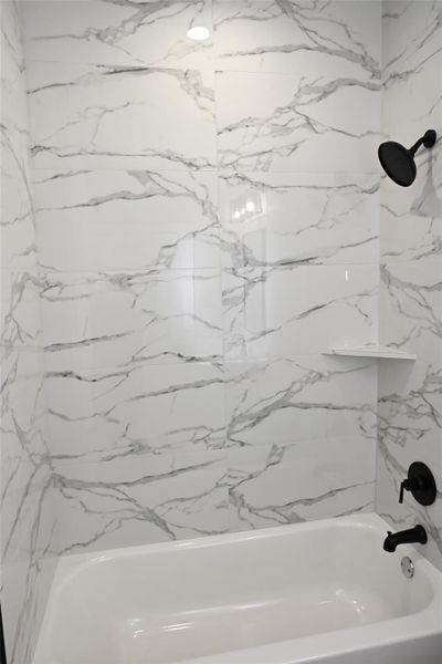 Full bath with a combined bath / shower with marble appearance