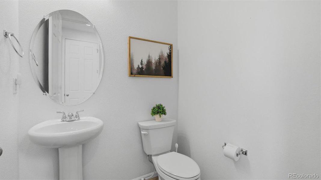 Powder Bathroom with pedestal sink and round mirror.