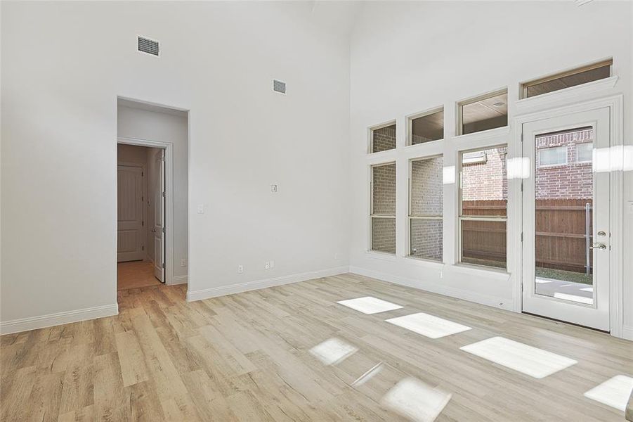 Empty room with a towering ceiling and light hardwood / wood-style flooring