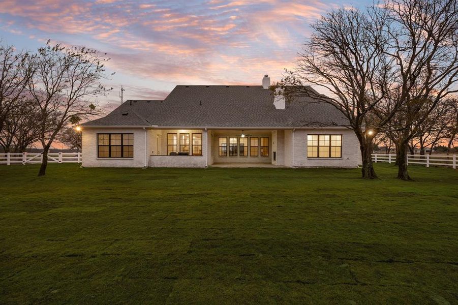 Rear view of property featuring a patio, a chimney, and a shingled roof