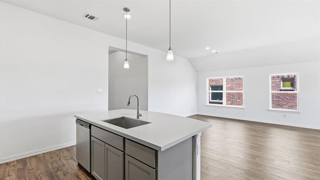 Kitchen island featuring a stainless steel undermount sink, a stainless steel dishwasher, and pendant lighting