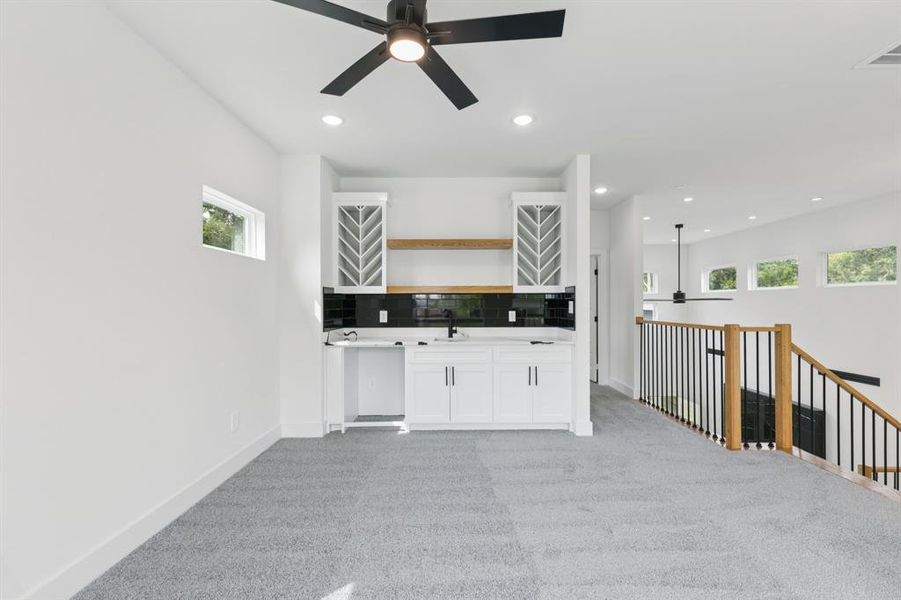 Bar area with ceiling fan, healthy amount of natural light, light colored carpet, backsplash, and recessed lighting