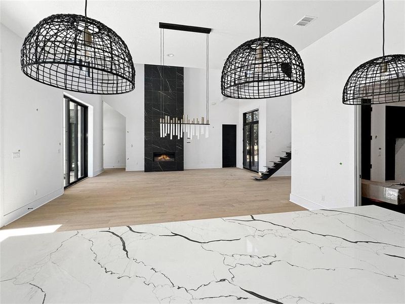 Captured from the kitchen's vantage point, this photo unveils a seamless transition to the expansive dining area and beyond to the inviting living room. Take note of the exquisite light fixtures that gracefully enhance the overall ambiance of this refined space.