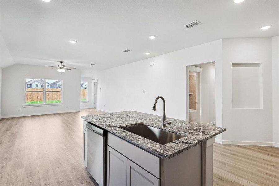 Kitchen with dishwasher, light hardwood / wood-style flooring, sink, ceiling fan, and stone counters