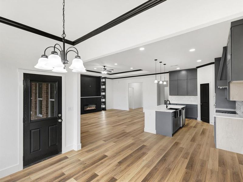 Kitchen with open floor plan, a chandelier, a glass covered fireplace, decorative light fixtures, and a kitchen island with sink Kitchen with open floor plan, a chandelier, a glass covered fireplace, decorative light fixtures, and a kitchen island with sink
