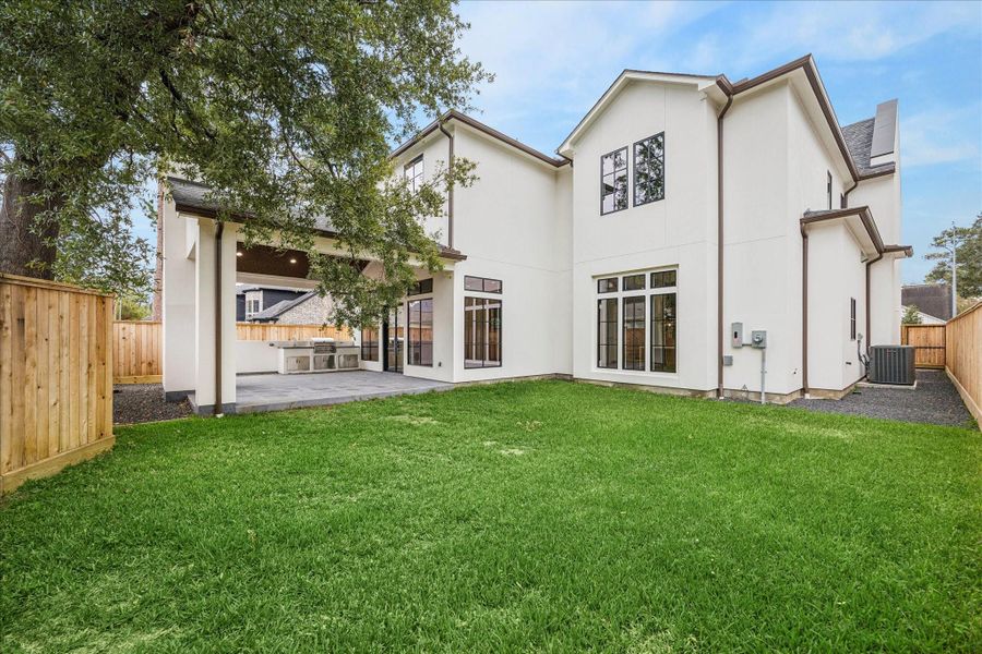 Wide yard space pairs with the deep covered patio for future pool plans, gardening, or play. Rear windows echo the home’s modern symmetry and fill interiors with natural light. Wide yard space pairs with the deep covered patio for future pool plans, gardening, or play. Rear windows echo the home’s modern symmetry and fill interiors with natural light.