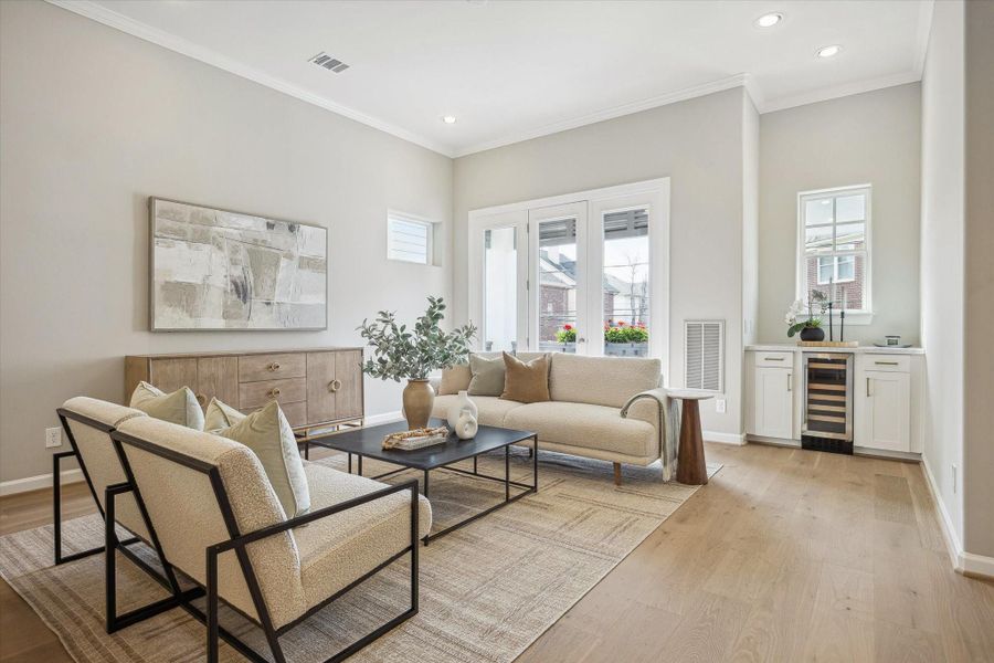 Living room has high ceiling, crown molding, and dry bar/coffee area.